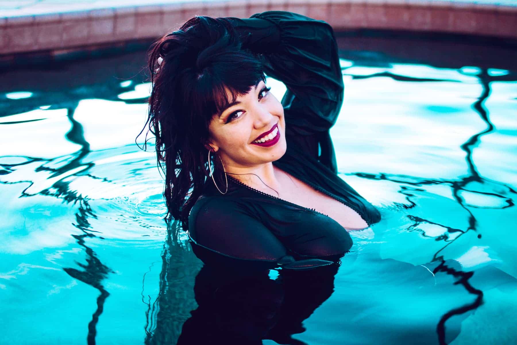 little puck in black dress in pool smiling